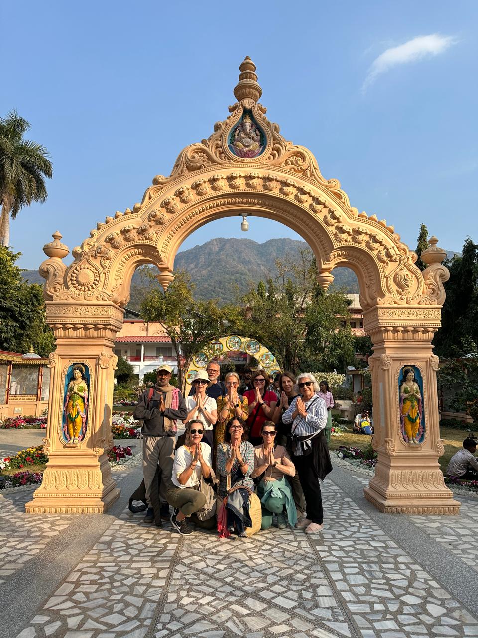 Grupo em namaskar sob o portal ornamentado de um ashram em Rishikesh